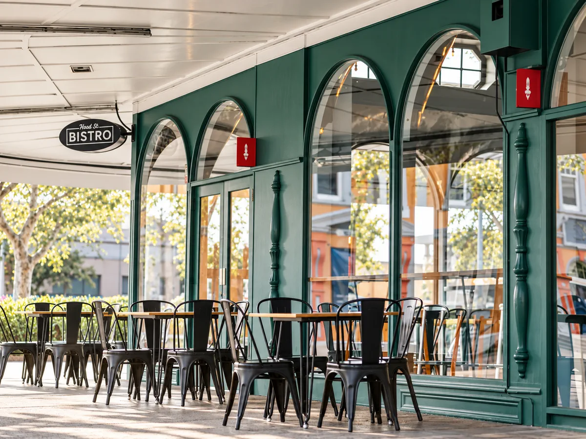 Covered outdoor seating beside the green bistro arches