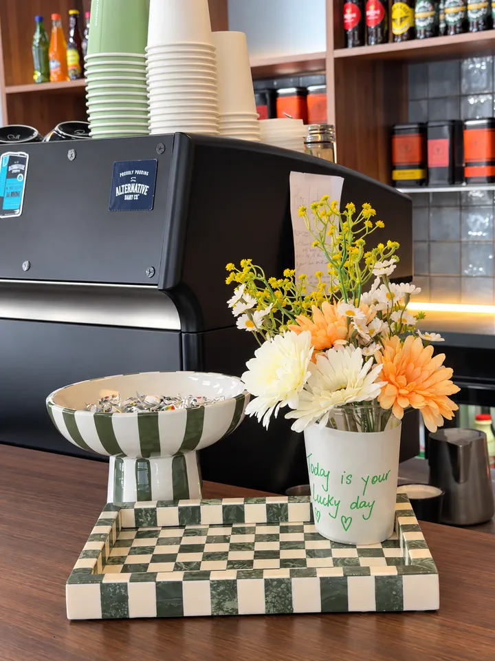 Flowers, cups and bottles arranged beside the coffee counter
