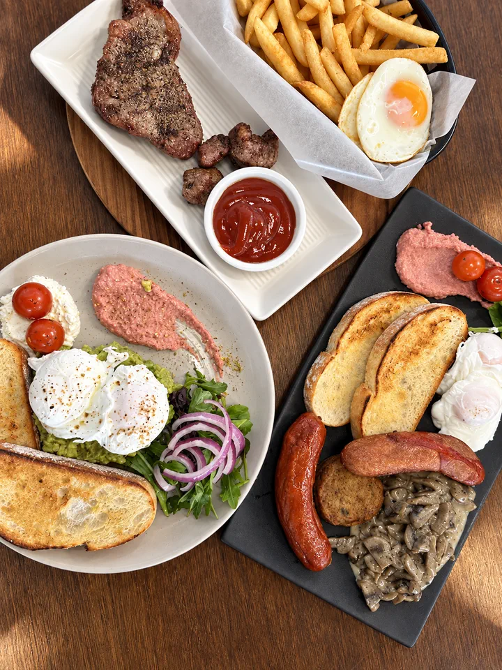Steak, eggs, toast, fries and brunch plates on a table